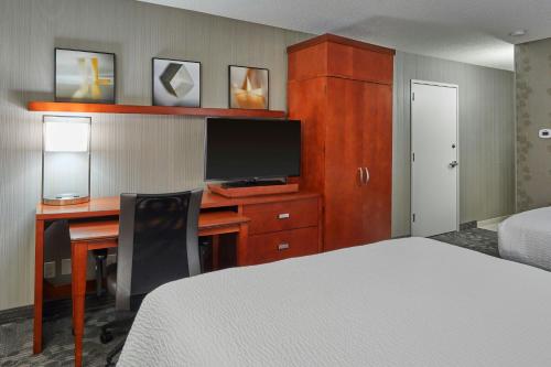 a bedroom with a desk with a bed and a television at Courtyard by Marriott Eugene Springfield in Springfield