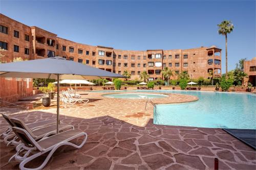 a swimming pool with chairs and an umbrella and a building at Marrakech River Palm in Dar Caïd Layadi