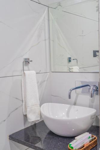 a white bathroom with a sink and a mirror at Hotel De Grand Dwarka-Near Jaipur Airport in Jaipur