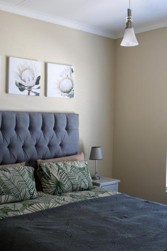 a bedroom with a large bed with a blue headboard at The Jade Somerset West Beachfront Apartment with Pool & Mountain Views in Cape Town
