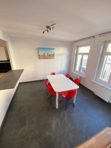 a dining room with a white table and red chairs at appartement hyper centre ville in Arras