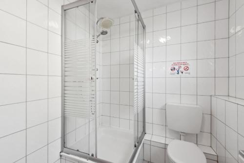 a white tiled bathroom with a shower and a toilet at Worker Apartment Goch in Goch