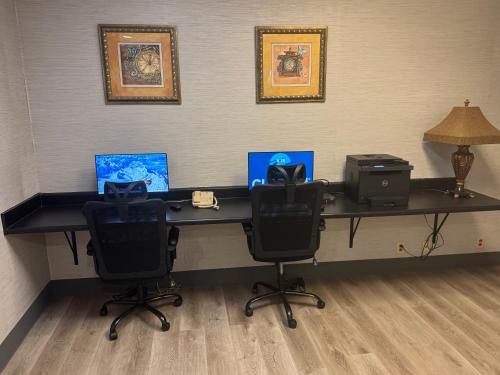 a desk with two laptops and a printer on it at Clarion Inn & Suites Dothan South in Dothan