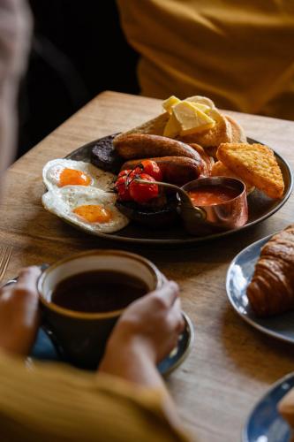- une table avec une assiette de produits pour le petit-déjeuner et une tasse de café dans l'établissement The Winning Post, à Windsor