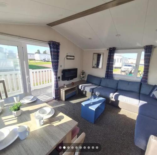 a living room with a blue couch and a table at 3 bed caravan with decking dishwasher en suite Haven Golden Sands in Mablethorpe