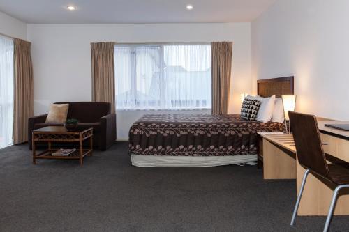 a hotel room with a bed and a desk and a window at Casino Court Motor Lodge in Christchurch