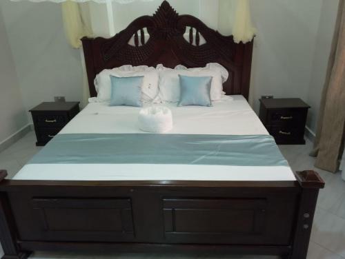 a bedroom with a large bed with a wooden headboard at Pthomes Official in Ruiru