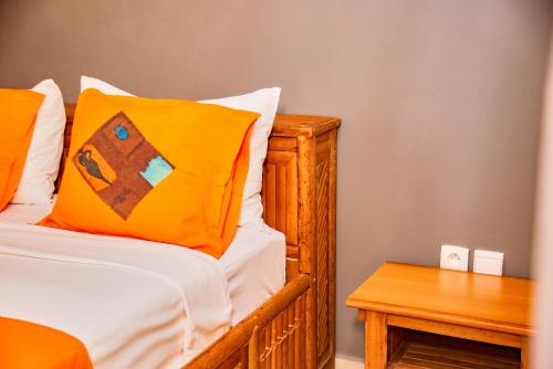a bedroom with a bed with an orange pillow and a table at CONGRESS HOTEL Yaoundé in Yaoundé