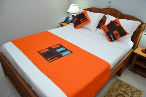 a bed with an orange blanket and pillows on it at CONGRESS HOTEL Yaoundé in Yaoundé