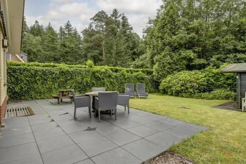 a patio with a table and chairs in a yard at Luxe boshuisje op kleinschalig park op de Veluwe in Putten