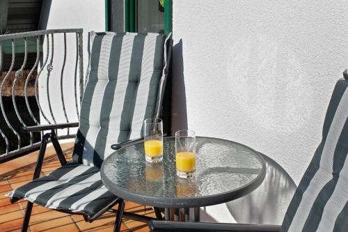 two glasses of orange juice on a glass table on a porch at Süd-Balkon an der schönen Peene in Demmin