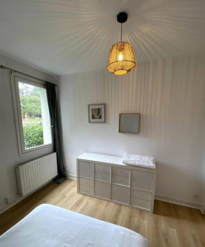 - une chambre avec un lit blanc et un lustre dans l'établissement Le Cosy Porte de Lyon, à Tassin-la-Demi-Lune