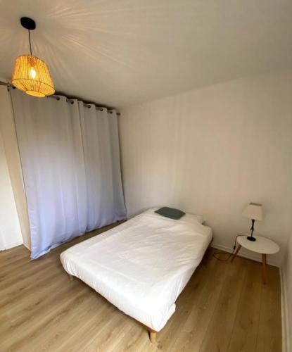 une petite chambre avec un lit blanc et une lampe dans l'établissement Le Cosy Porte de Lyon, à Tassin-la-Demi-Lune