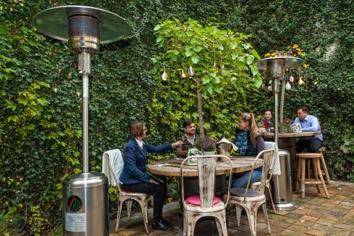 a group of people sitting at a table in a garden at Cathedral Prague Apartments in Prague