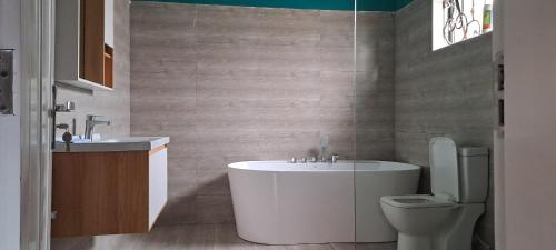 a bathroom with a tub and a toilet and a sink at Hillside Inn lubowa in Kampala