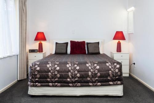 a bedroom with a large bed with two lamps at Casino Court Motor Lodge in Christchurch