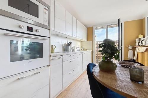 une cuisine avec des armoires blanches et une table en bois dans l'établissement Superb apartment with large terrace, à Paris