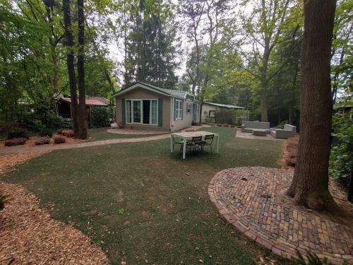 a backyard with a picnic table and a house at Bos Chalet Huize Vriendschap in Hattemerbroek