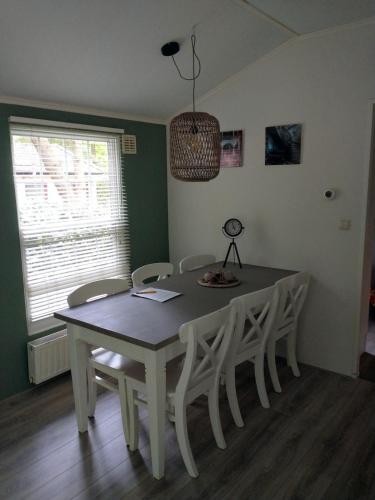 a dining room table with white chairs and a lamp at Bos Chalet Huize Vriendschap in Hattemerbroek