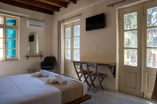 a bedroom with a bed and a desk and windows at Vavana Studios in Symi