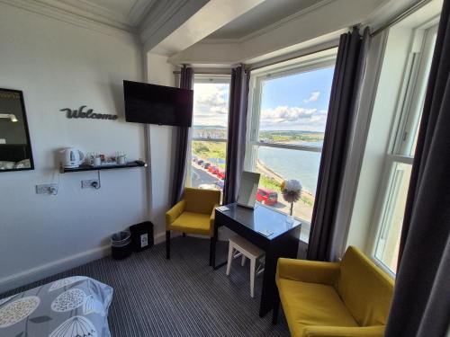 a hotel room with a desk and a view of the water at Miricia Guest House in Scarborough