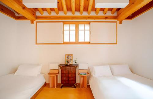 Dos camas en una habitación con techos de madera. en Numaru Stay - Luxury Private Hanoks in Seochon, Seoul, en Seúl