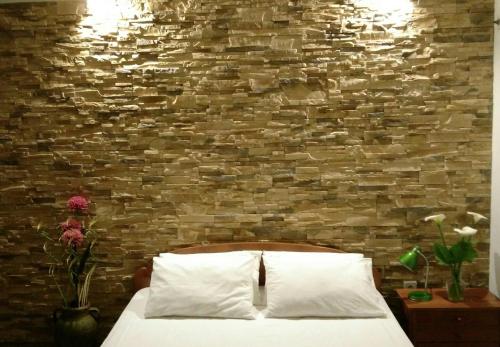 a bedroom with a brick wall and a bed with white pillows at Apartments Jadran in Herceg-Novi