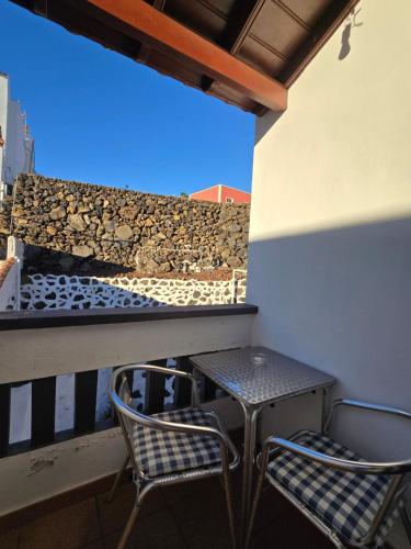 a table and chairs on a balcony with a stone wall at Pensión Los Volcanes in Fuencaliente de la Palma