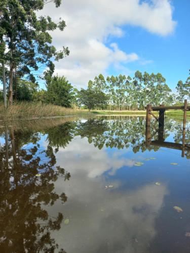 a body of water with a bridge and trees at Propriedade inteira - duas suítes, pavilhão e espaço externo in Passo De Torres