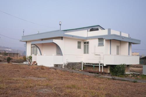 a white house on the side of a field at Amazing Resort in Cherrapunji
