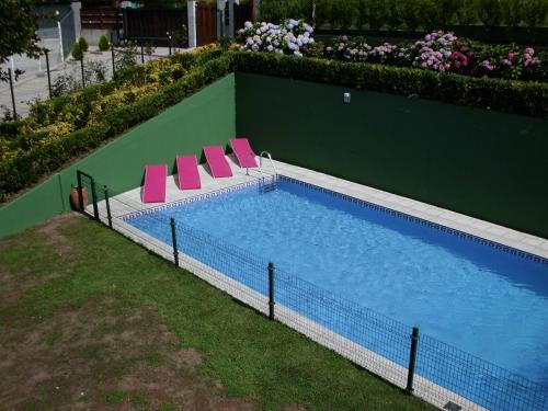 ein Pool mit zwei rosa Liegestühlen daneben in der Unterkunft La Casa de las Ostras in Mogro