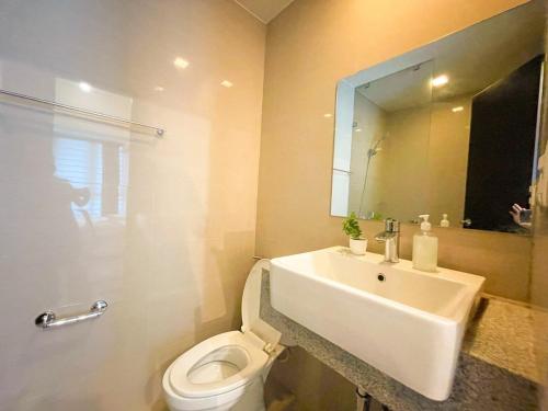 une salle de bain avec un lavabo, des toilettes et un miroir dans l'établissement Elegant BGC Condo Across Mitsukoshi Mall #upt27p, à Manille