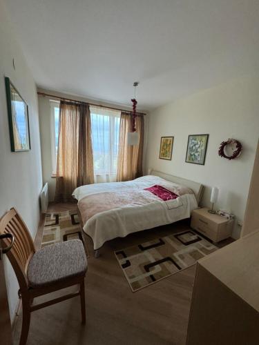 a bedroom with a bed and a chair in it at Pirin Golf View Apartment Bansko in Bansko