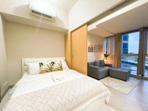 ein Schlafzimmer mit einem großen weißen Bett und einer Couch in der Unterkunft Prime BGC 1BR Near Mitsukoshi Mall #upt16m in Manila