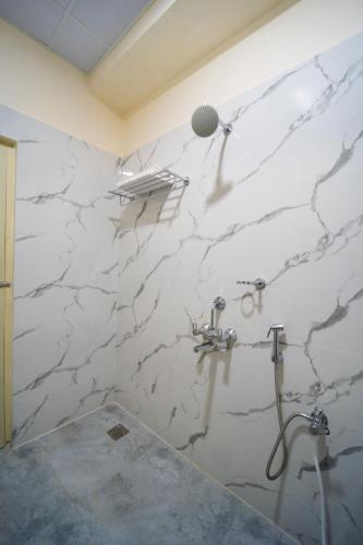 a white marble bathroom with a shower and a sink at VR PARADISE Inn in Kelambākkam