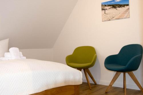 two green chairs sitting next to a bed at 'Lieblingsbude' in Langeoog