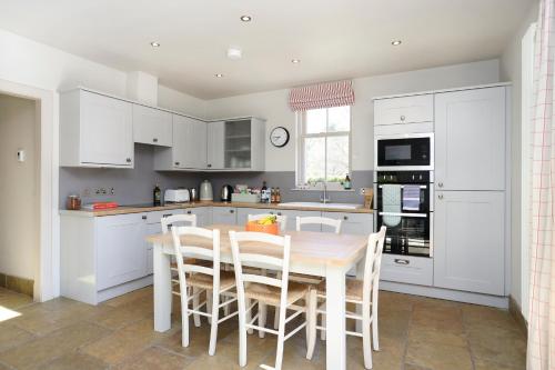a kitchen with white cabinets and a table and chairs at JOIVY The Lodge At Gilmerton House, North Berwick in North Berwick