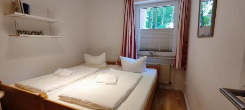 Dos camas en una habitación pequeña con ventana. en 'Edes Huus', en Langeoog