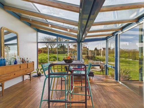 une véranda avec une table, des chaises et des fenêtres dans l'établissement Superbe villa à Plouguerneau les pieds dans l'eau, à Plouguerneau