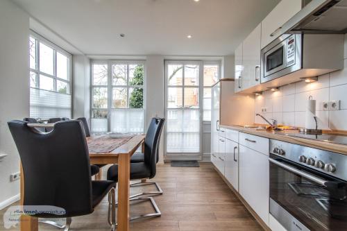 een keuken met een houten tafel en zwarte stoelen bij Ferienwohnung 1 im 'BÖTTCHER HUUS' in Langeoog
