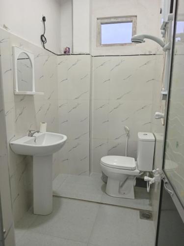 a white bathroom with a toilet and a sink at Kandy Horizon Homestay in Kandy