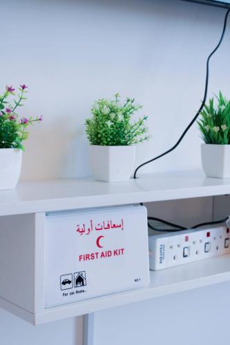 a white table with three potted plants on it at Yas Island Waters Edge Studio by Central Stay in Abu Dhabi