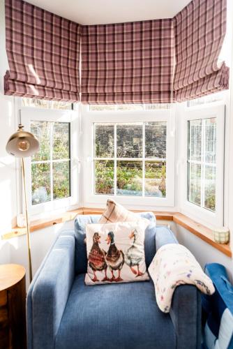 a blue couch in a living room with windows at Cosy Days Cottage in Skipton