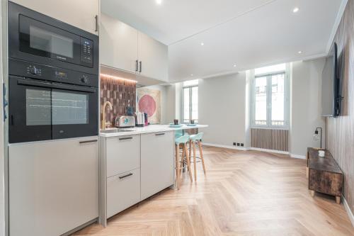 une cuisine avec des armoires blanches et un appareil noir dans l'établissement Bel appartement centre Cannes 1min de la Croisette, à Cannes