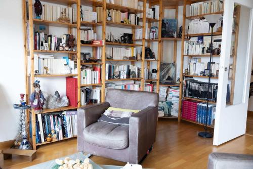 une chambre avec une chaise et des étagères avec des livres dans l'établissement Spacious Apt With Terrace And Parking, à Vanves