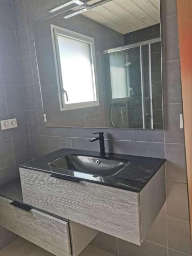 une salle de bain avec un lavabo et un miroir dans l'établissement Jolie petite maison à 7 min à pied de la plage pour 6 pers, à Saint-Nic
