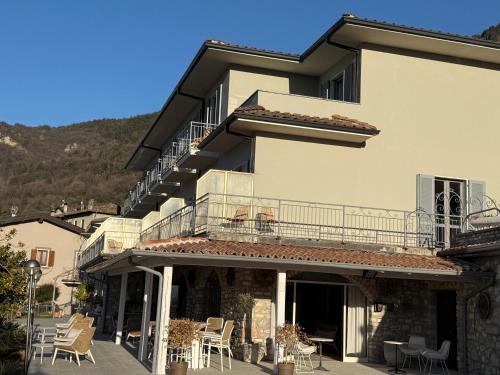 a building with a balcony and tables and chairs at Hotel MioMio in Tignale