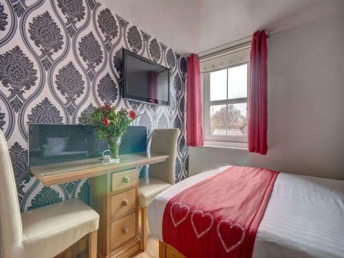 a bedroom with a bed and a desk and a television at Elford House - Whitby in Whitby