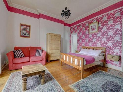 a bedroom with a bed and a red couch at Elford House - Whitby in Whitby