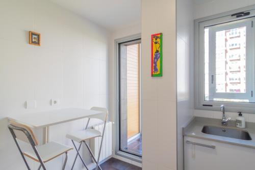 a kitchen with a sink and a table and a window at Apartamento Holidea Parque las Llamas in Santander